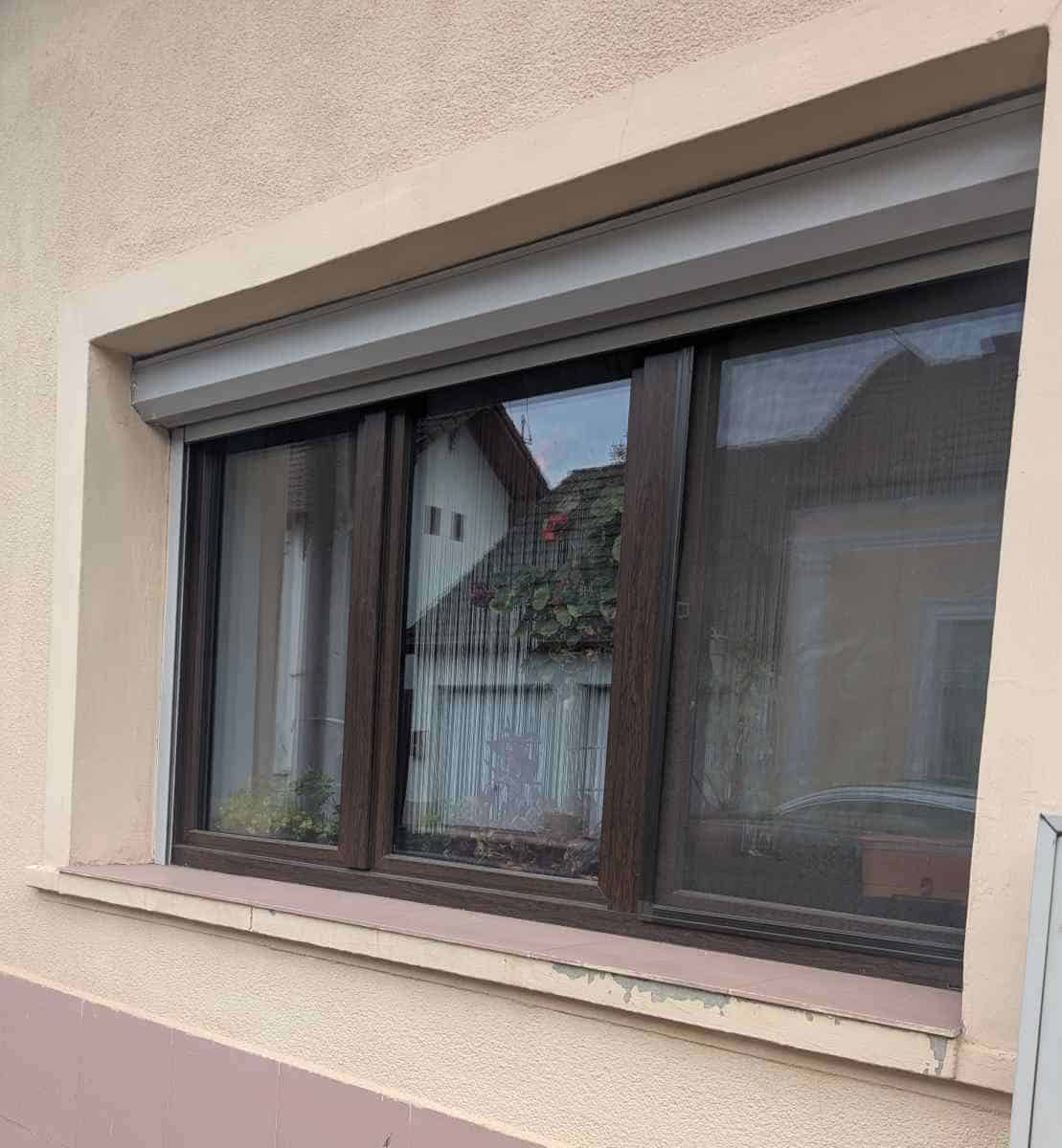 Glaf exterior improvizat din gresie pe o casă cu ferestre termopan — tencuiala se degradează sub fereastră din cauza lipsei picurătorului