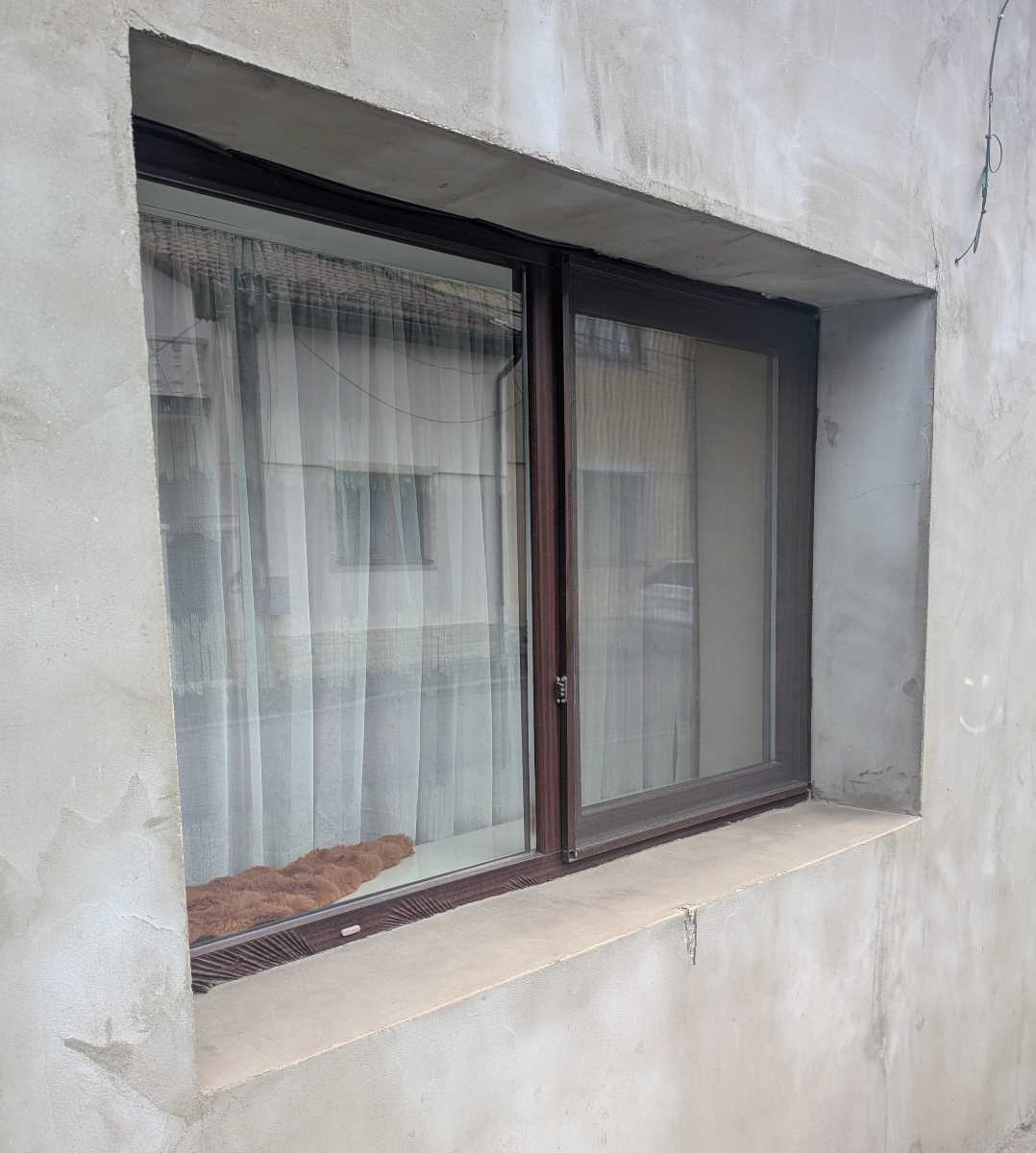 Fereastră termopan fără glaf exterior pe fațadă netencuită, exemplu de construcție nefinalizată fără protecție sub fereastră