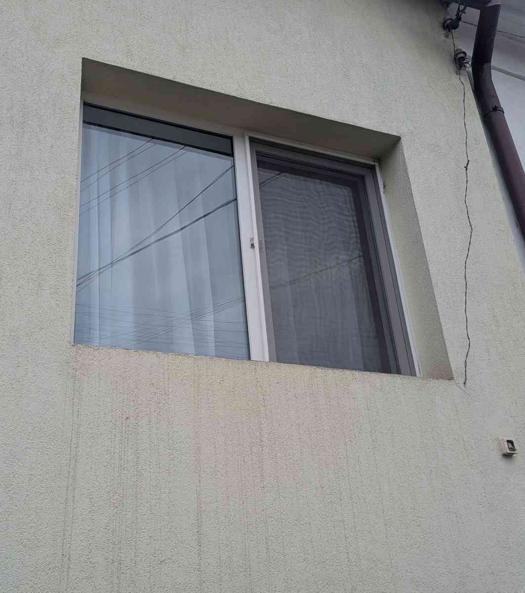 Fațadă cu pete și dâre de scurgere sub fereastră, tencuială deteriorată din cauza lipsei glafului exterior
